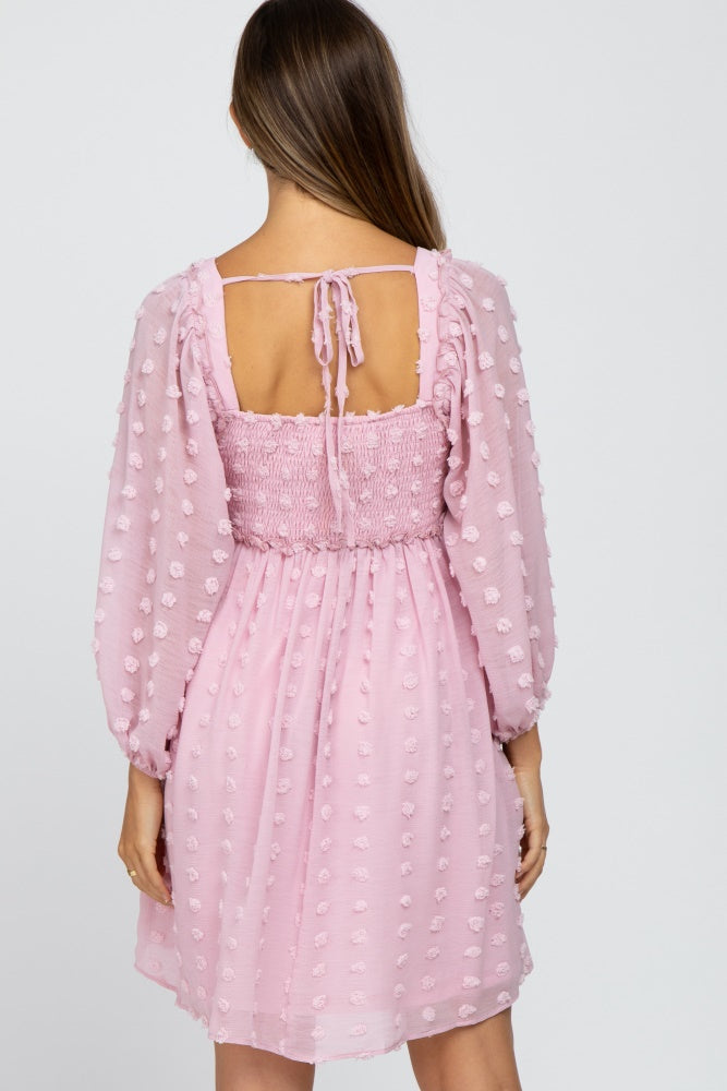 woman wearing a light pink maternity dress with puff sleeves and a smocked bodice, back view