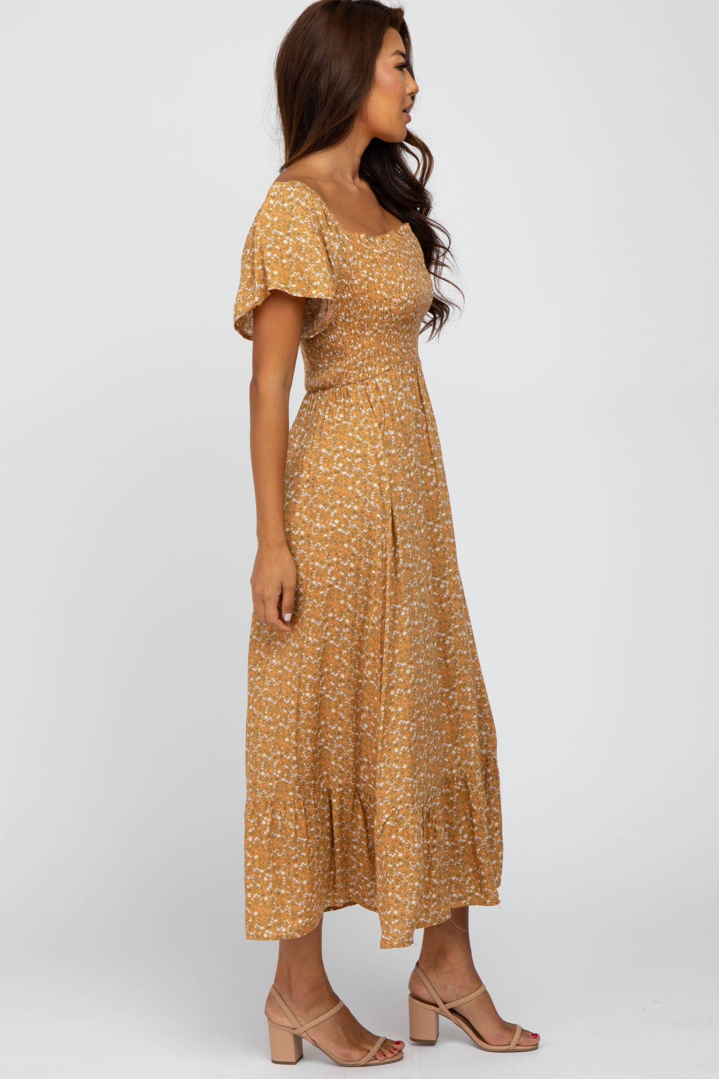 woman wearing a mustard yellow floral midi dress with a smocked bodice and short puff sleeves