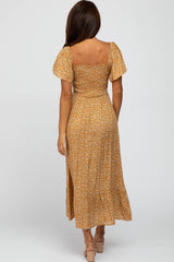 woman wearing a mustard yellow floral maxi dress with short puff sleeves and a fitted bodice, shown from the back