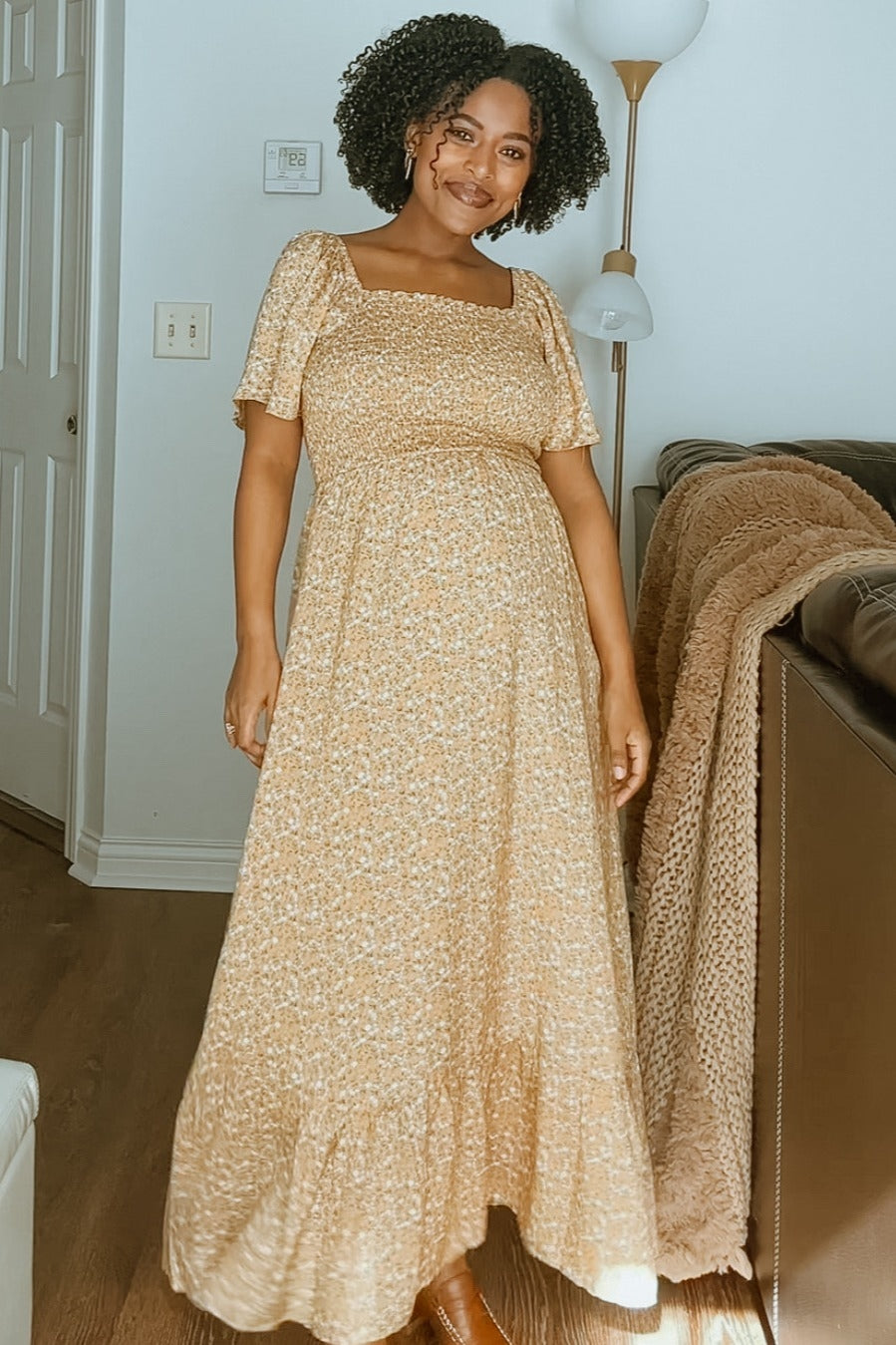 woman wearing a yellow floral maternity maxi dress with puffed sleeves and a visible baby bump