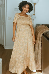 woman wearing a yellow floral maternity maxi dress with puffed sleeves and a visible baby bump