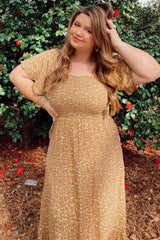 woman wearing a mustard yellow floral print maxi dress with short sleeves and a smocked bodice, posing outdoors