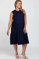 Smiling woman wearing a navy blue sleeveless tiered maternity midi dress and white block heel sandals