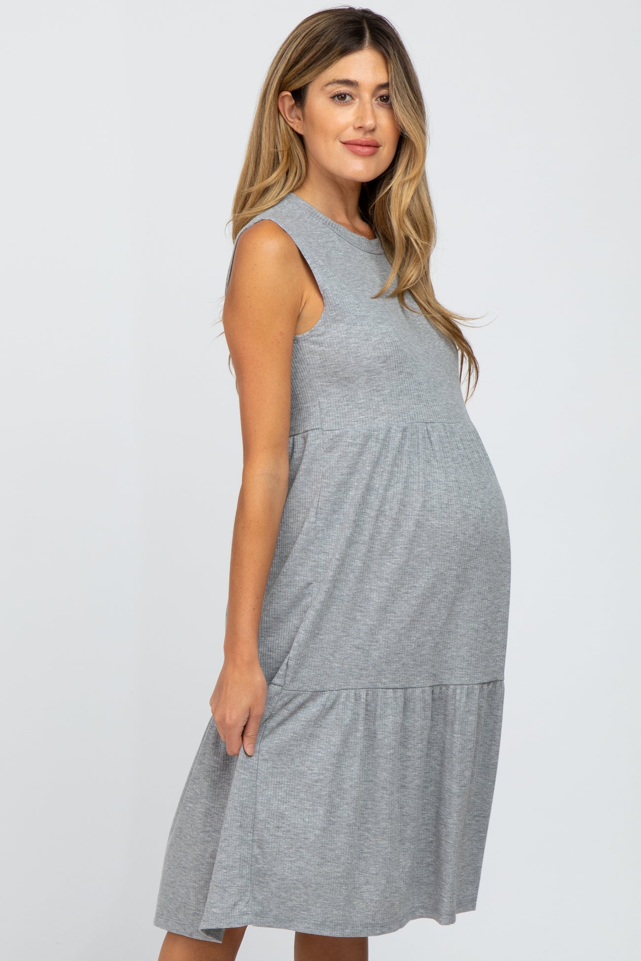 pregnant woman wearing a sleeveless grey ribbed maternity dress with a tiered skirt