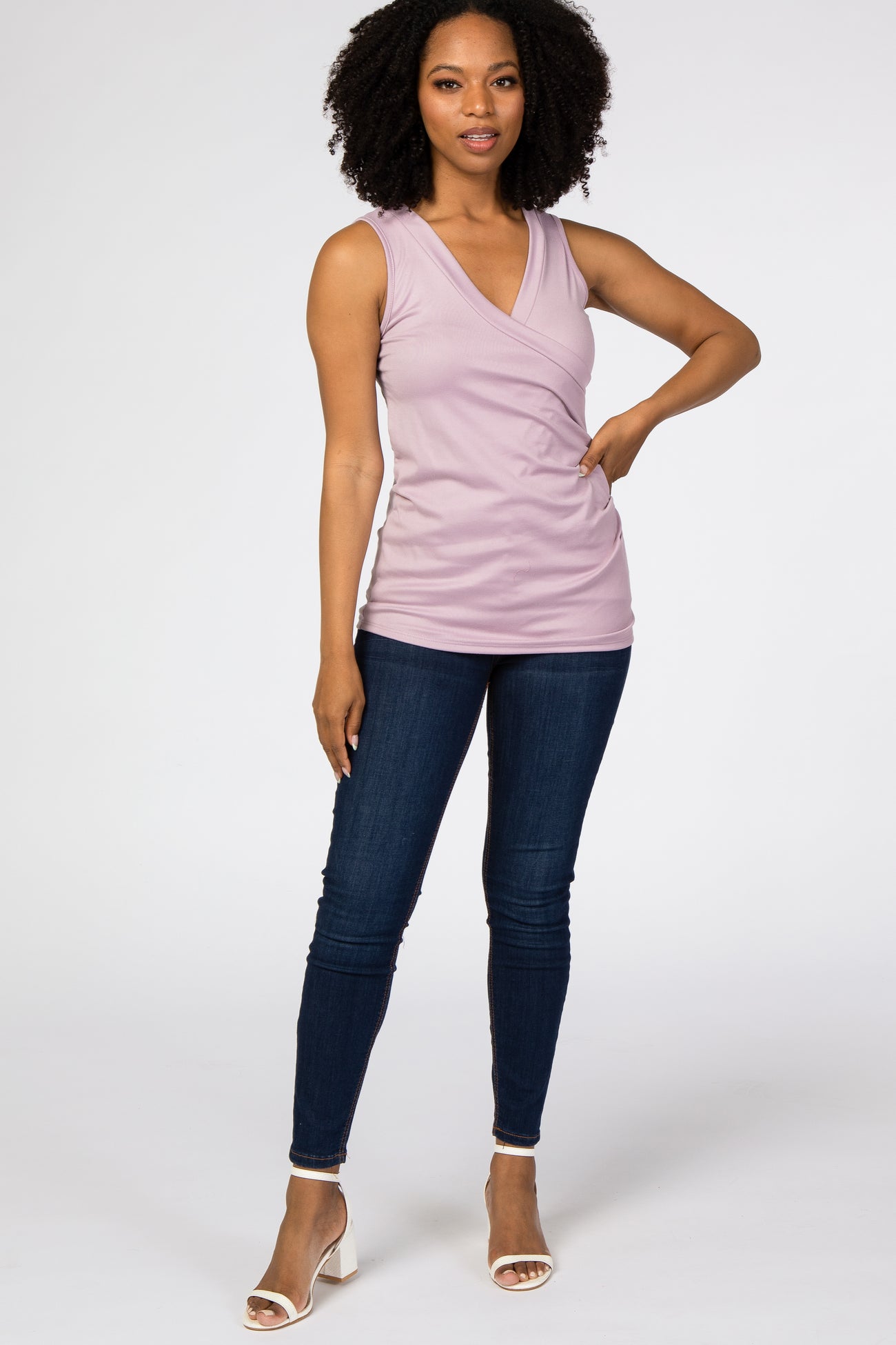 woman wearing a lavender sleeveless wrap top with a v-neckline and high-waisted dark jeans