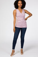 woman wearing a lavender sleeveless wrap top with a v-neckline and high-waisted dark jeans
