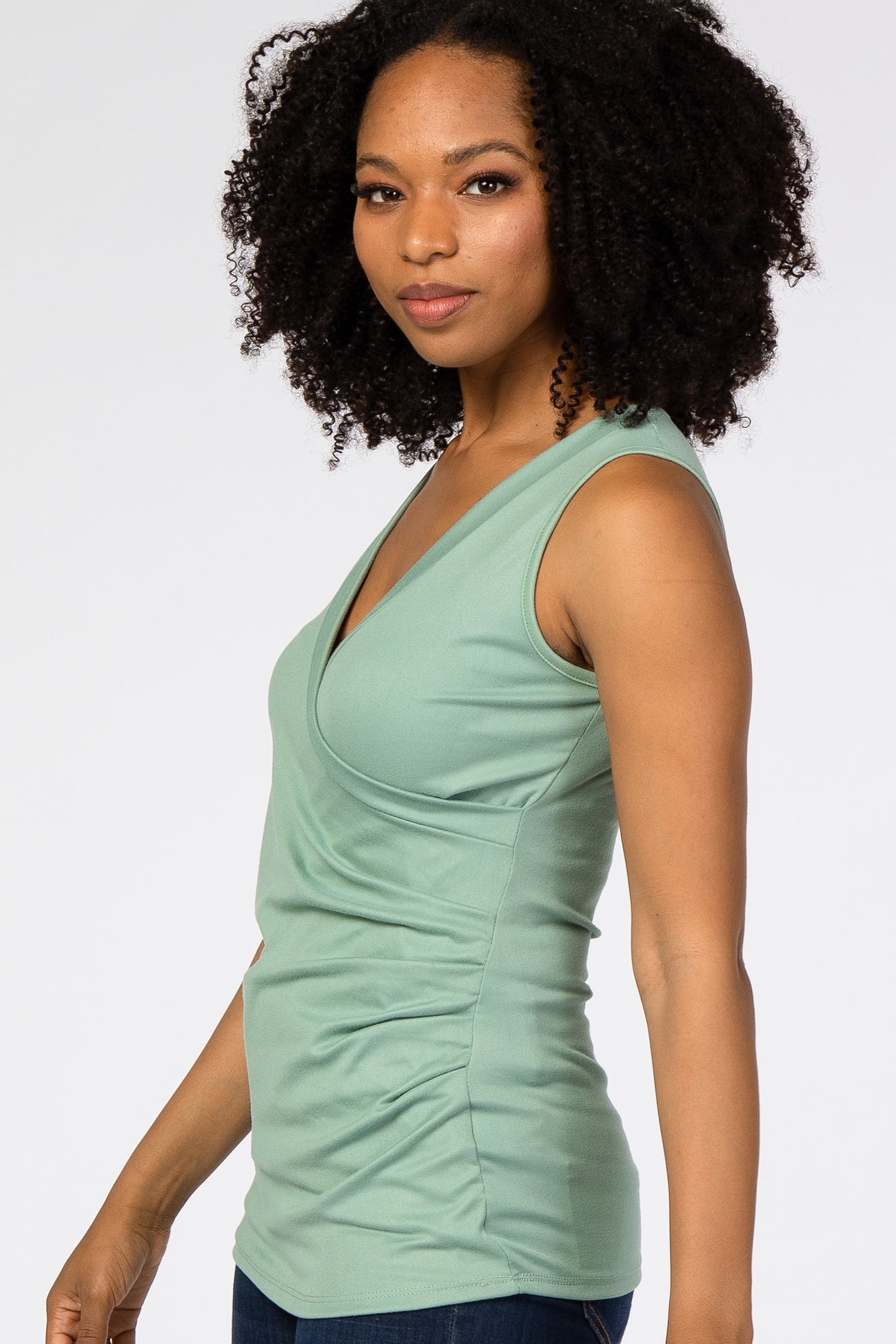 woman wearing a light green sleeveless wrap top with ruching details and a relaxed fit