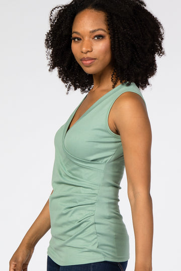 woman wearing a light green sleeveless wrap top with ruching details and a relaxed fit
