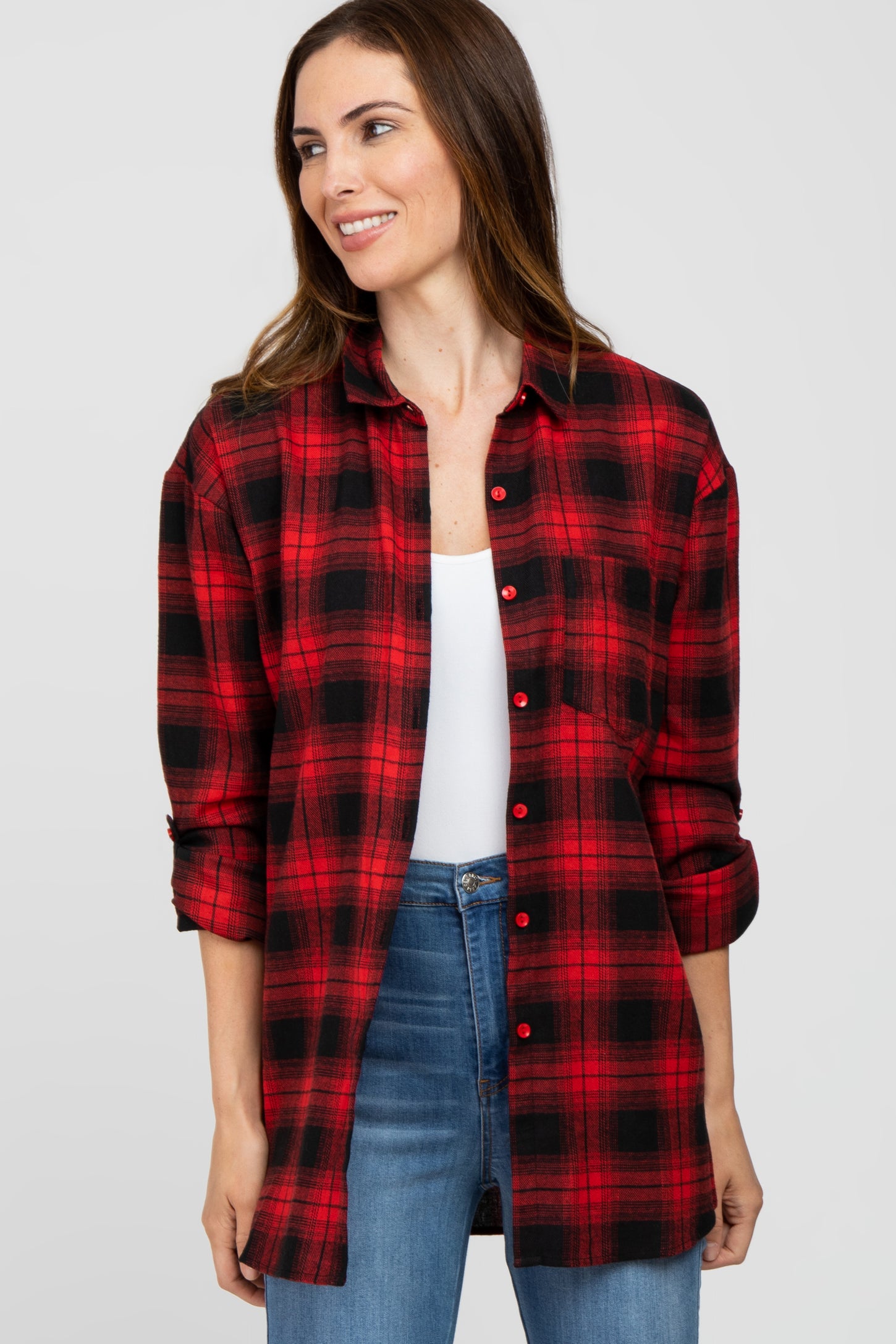 woman wearing a red and black plaid button-up shirt with rolled sleeves and a white tank top underneath