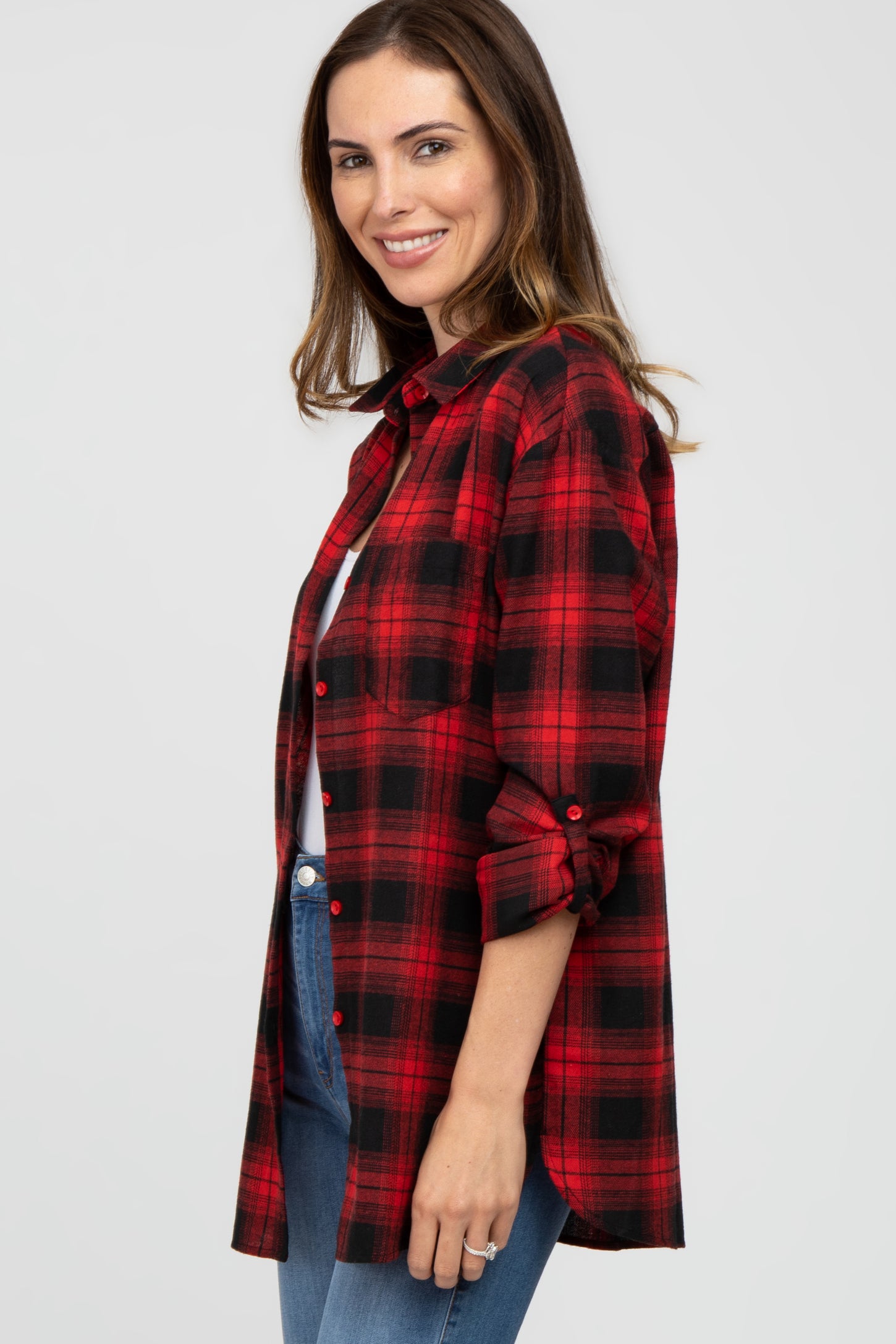 woman wearing a red and black plaid long sleeve shirt with rolled sleeves and blue jeans
