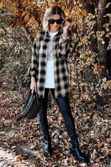 woman wearing a black and yellow plaid oversized shirt, graphic t-shirt, black leggings, and ankle boots, posing outdoors