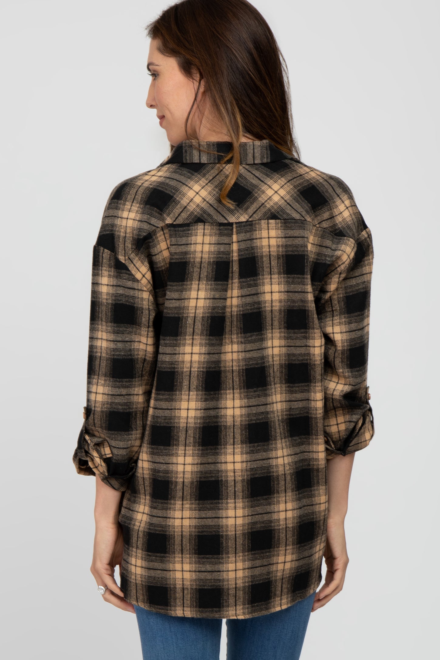 woman wearing a brown and black plaid flannel shirt, showcasing the back view and rolled sleeves
