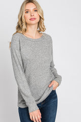 blonde woman wearing a grey long sleeve waffle knit sweater and blue jeans