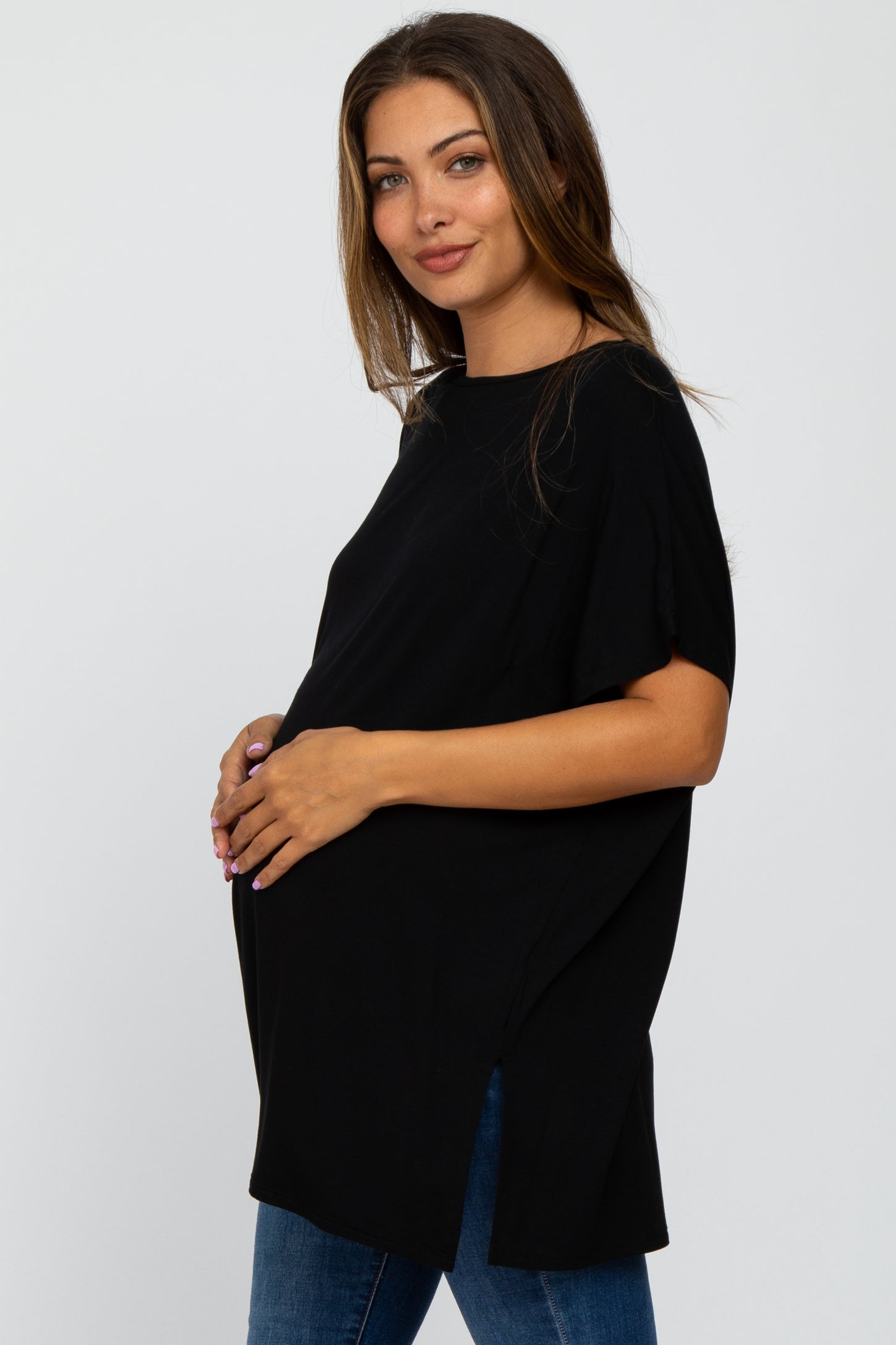 Pregnant woman wearing a black short sleeve maternity tunic top and blue jeans