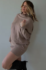 woman wearing a taupe oversized sweater and matching mini skirt with knee-high black boots