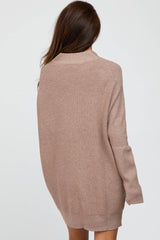 woman wearing a cozy light brown oversized sweater with a high collar and long sleeves, viewed from the back