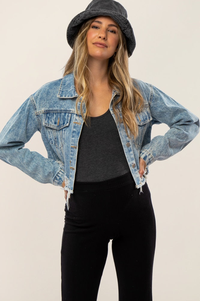 woman wearing a light wash cropped denim jacket with frayed hem and a black bucket hat