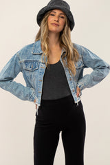 woman wearing a light wash cropped denim jacket with frayed hem and a black bucket hat