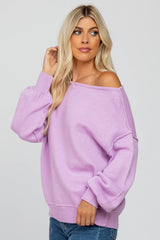 woman with blonde hair wearing a light purple off-the-shoulder knit sweater and blue jeans