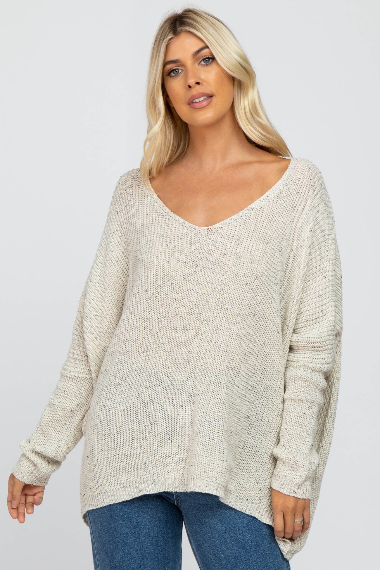 woman wearing a cream oversized v-neck knit sweater with long sleeves and a relaxed fit