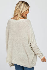 woman wearing a light beige oversized knit sweater with ribbed details, shown from the back