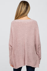 woman wearing a loose-fitting pale pink maternity sweater, seen from the back