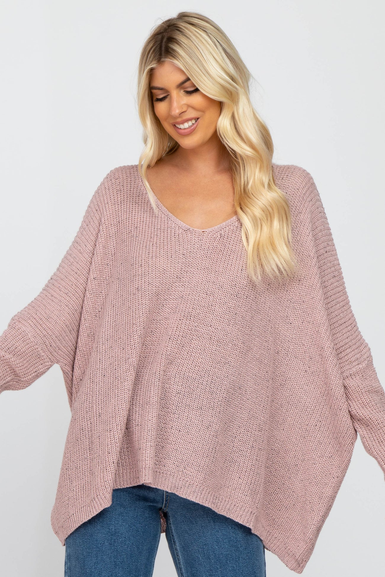 woman wearing a soft pink oversized knit sweater with a v-neck and wide sleeves