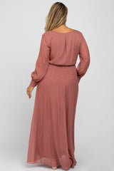 woman wearing a dusty rose long sleeve maternity plus dress with a cinched waist and flowing skirt, viewed from the back