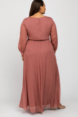 woman wearing a rose-colored long sleeve maxi dress with a cinched waist, seen from the back