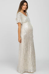 woman wearing a silver sequin maternity gown with a flattering v-neck and flutter sleeves, highlighting her baby bump