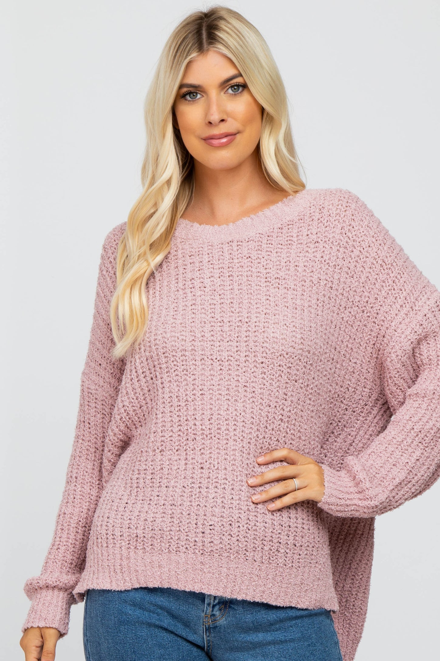 blonde woman wearing a mauve oversized popcorn knit sweater and blue jeans