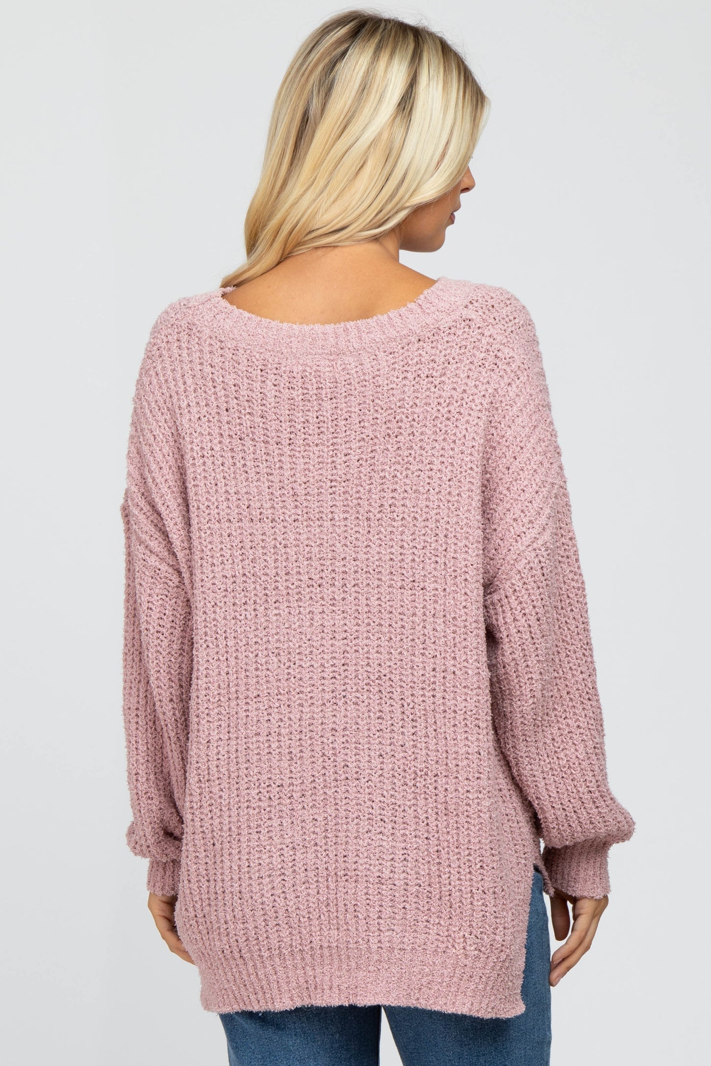 Back view of a woman wearing a mauve oversized popcorn knit sweater with a v-neckline and long sleeves