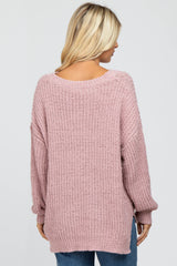 Back view of a woman wearing a mauve oversized popcorn knit sweater with a v-neckline and long sleeves