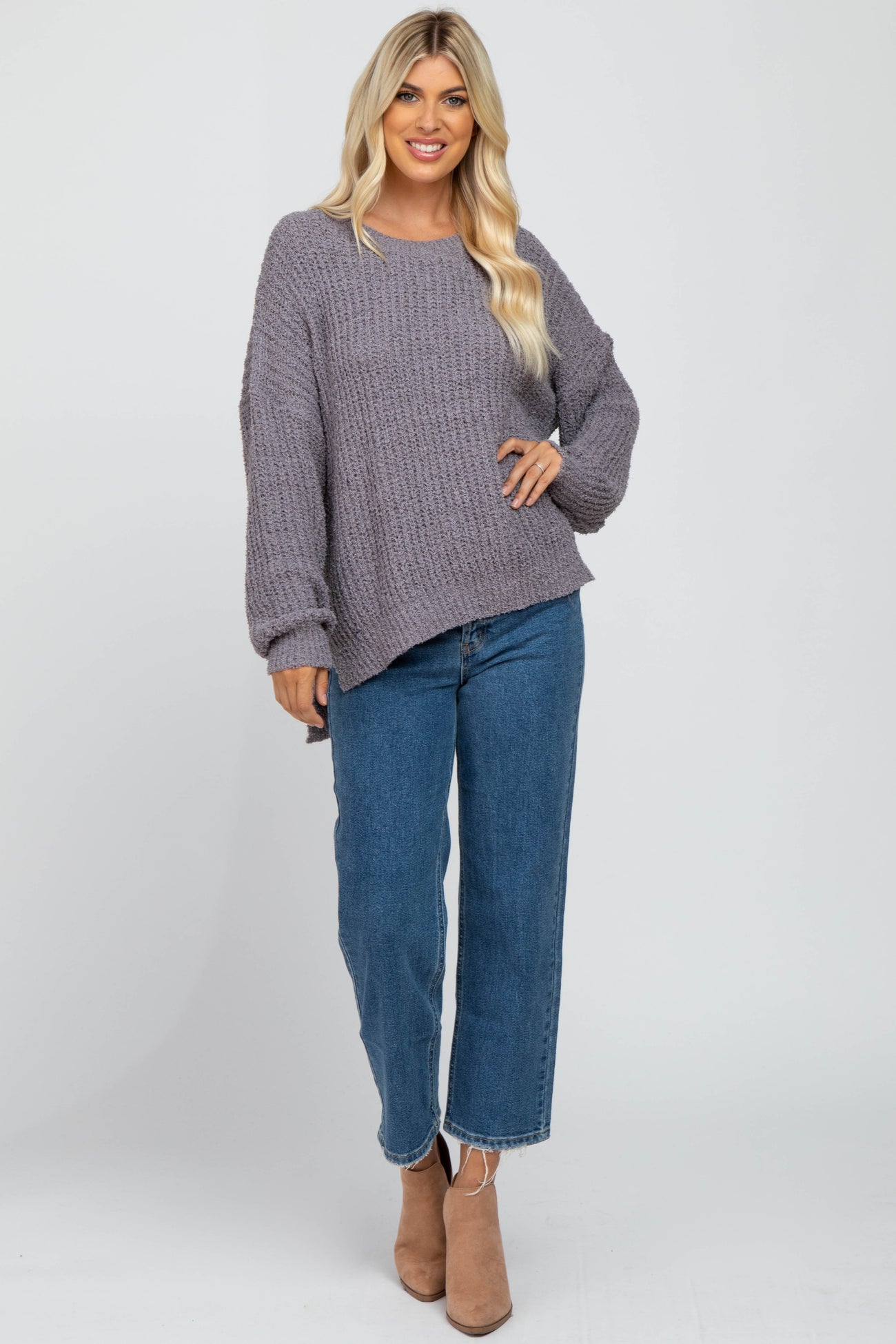 woman wearing oversized purple popcorn knit sweater and blue straight leg jeans with tan ankle boots