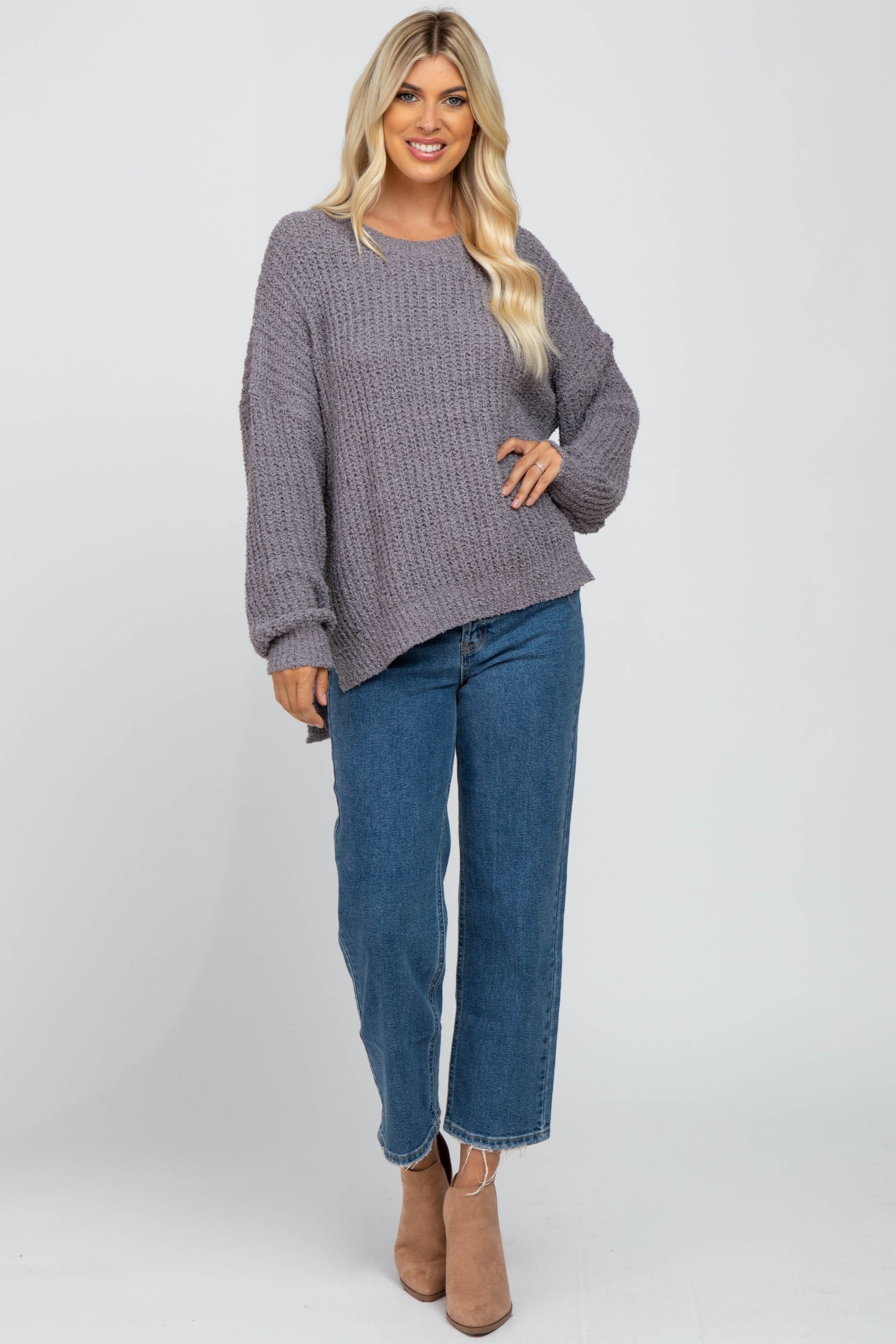 woman wearing oversized purple popcorn knit sweater and blue straight leg jeans with tan ankle boots