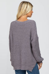 back view of a woman wearing a mauve oversized popcorn knit sweater and blue jeans
