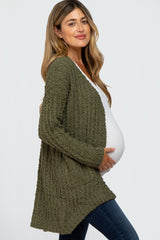 pregnant woman wearing olive green popcorn knit maternity cardigan and white top