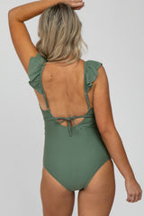 woman wearing a green maternity one-piece swimsuit with ruffled sleeves, showing an open back and tied detail