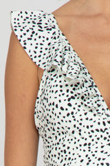 maternity wear in a sleeveless dress with ruffled shoulder detail and black spots on a light background