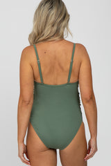 woman wearing a green maternity swimsuit with adjustable straps and a ribbed texture, showing the back view