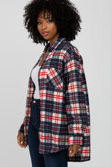 Woman with curly hair wearing a red, white, and blue plaid flannel shirt over a white top and jeans