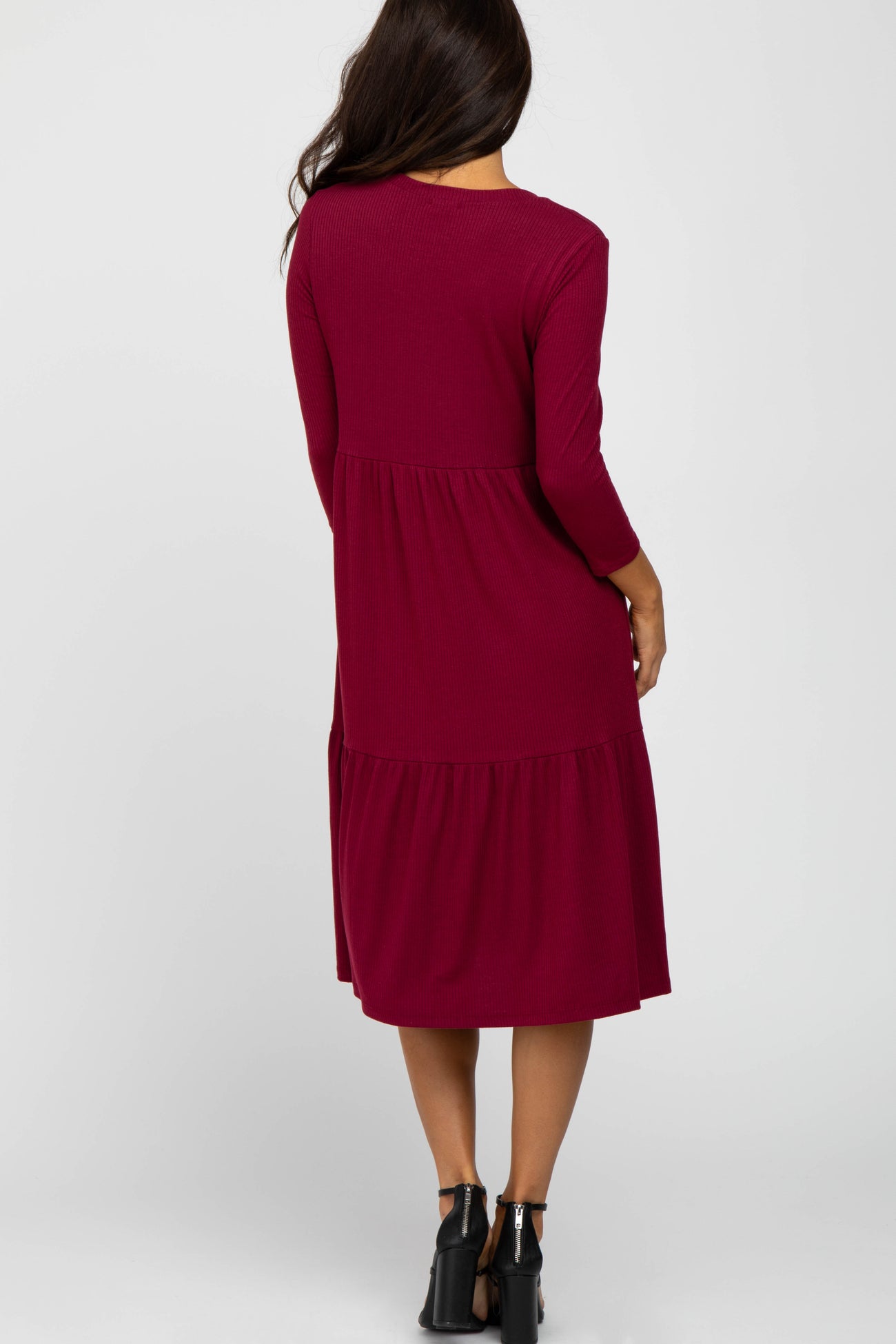woman wearing a long burgundy tiered dress with three-quarter sleeves seen from the back