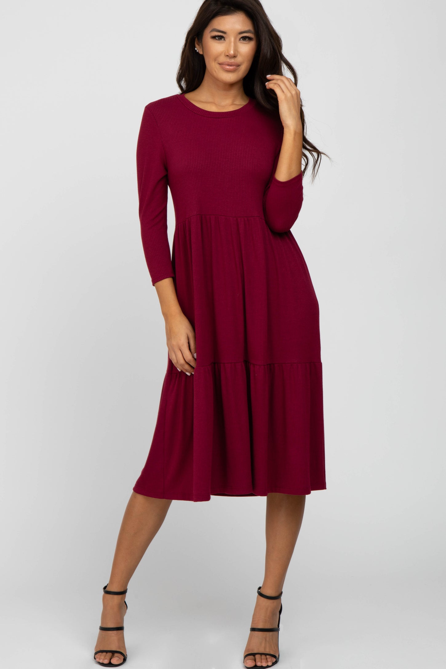 woman wearing a burgundy three-quarter sleeve midi dress with a tiered skirt and strappy black heels