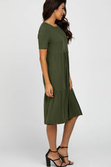 woman wearing a short sleeve olive green tiered midi dress with a relaxed fit and strappy black heels