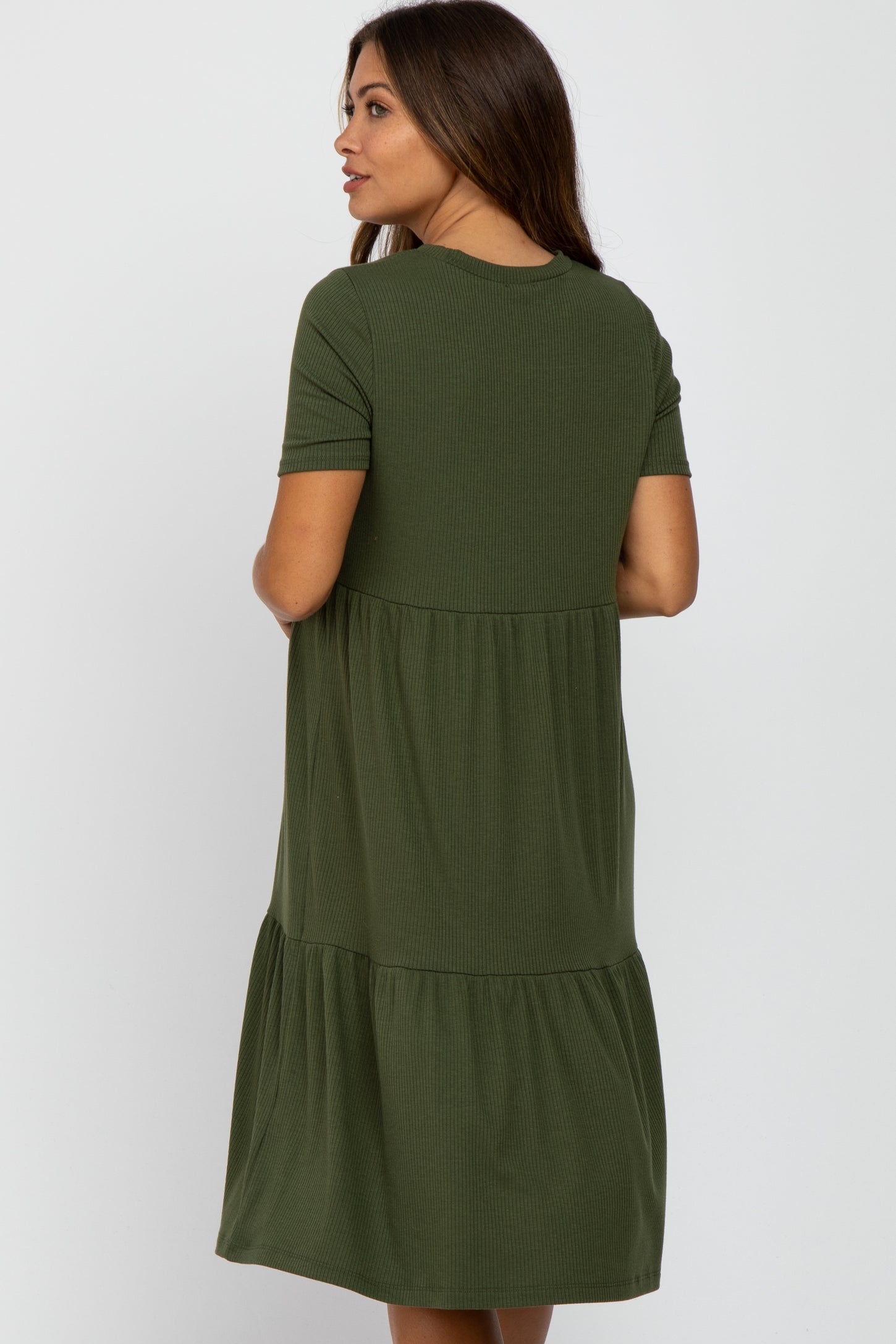 woman wearing an olive green maternity dress with short sleeves and a tiered design, showing the back view