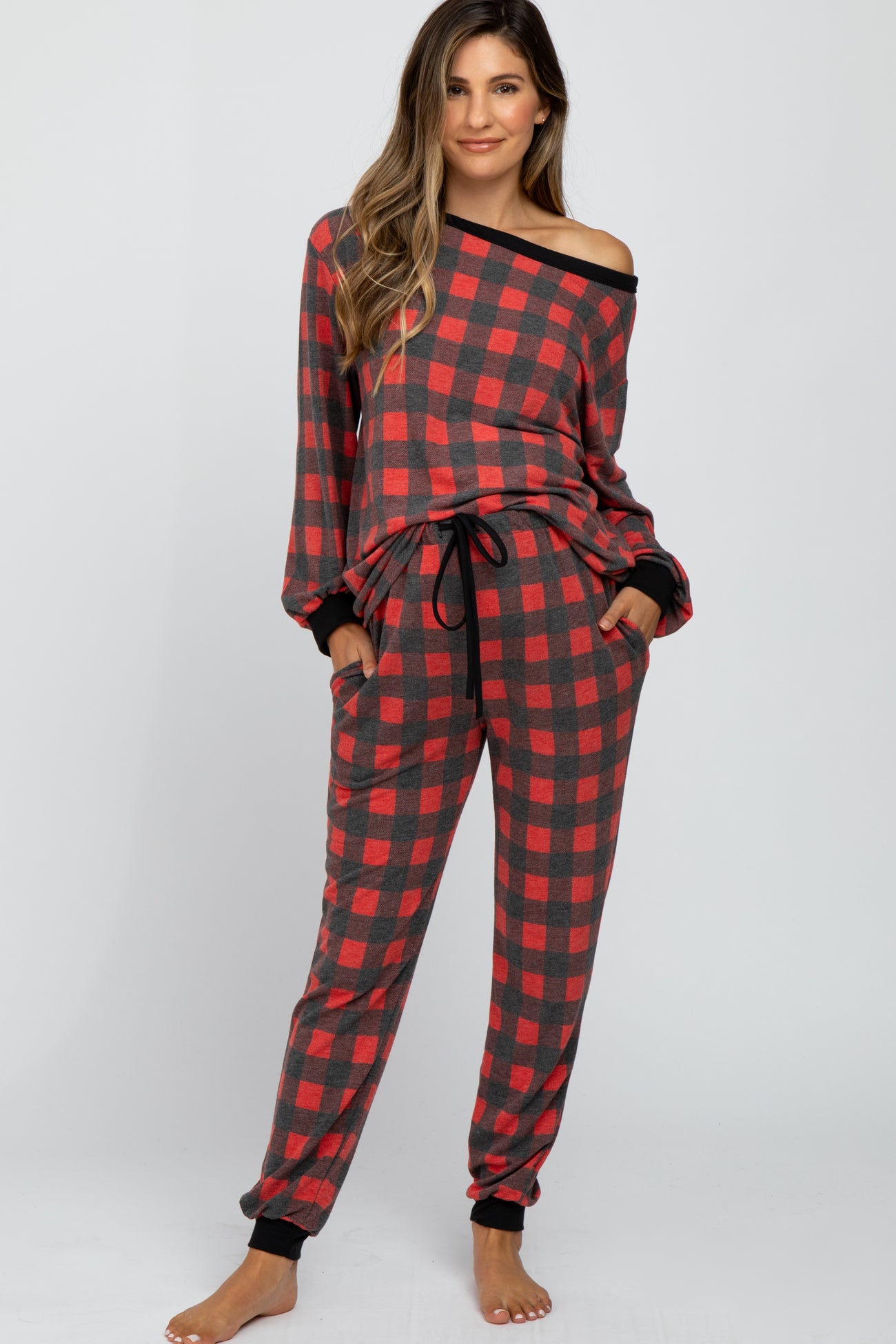 woman wearing a red and black plaid maternity pajama set with an off-the-shoulder top and pants
