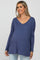 Smiling pregnant woman wearing a blue long sleeve v-neck maternity top and light wash jeans