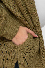 close up of a hand in the pocket of an olive green chunky knit cardigan with pointelle stitch details