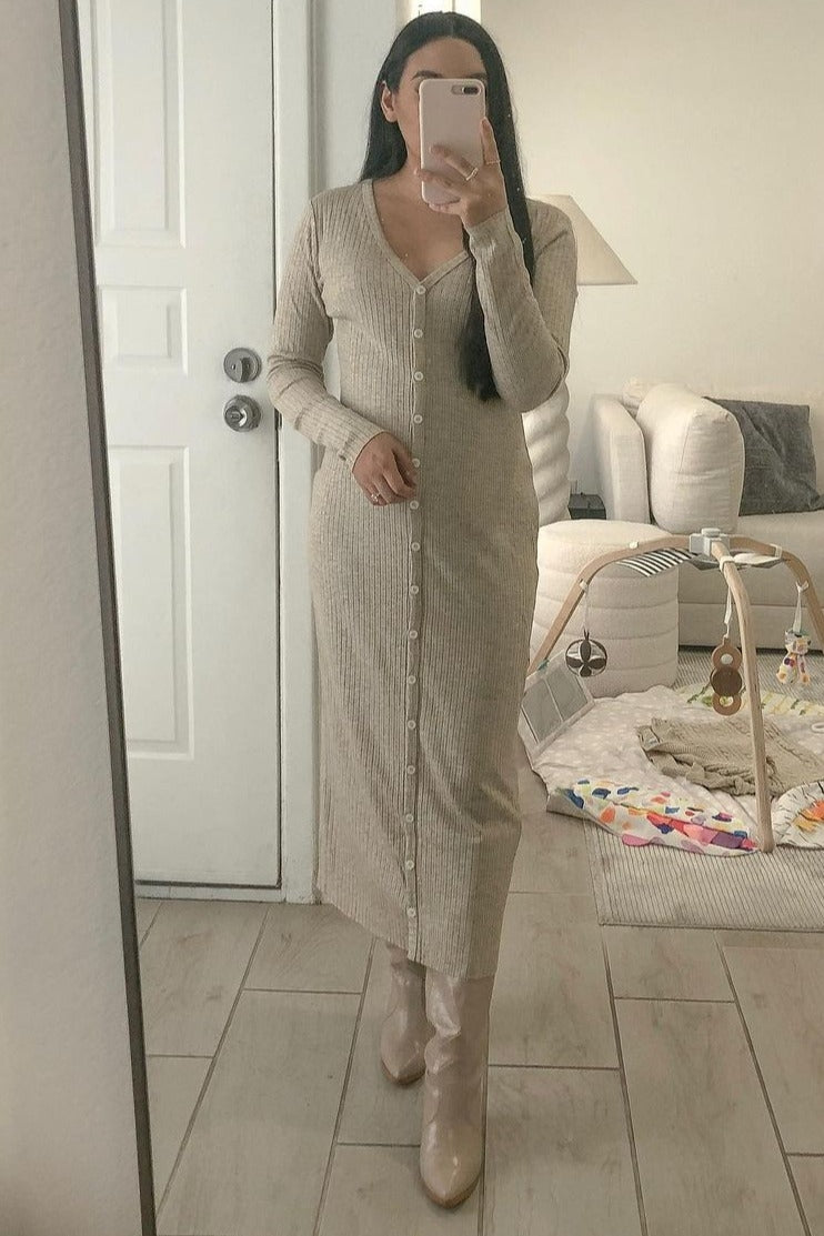 woman in beige ribbed button-down maxi dress and matching boots taking a mirror selfie in a living room