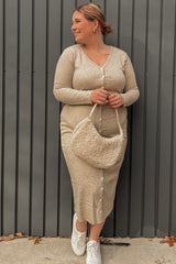 Woman in a beige ribbed button-down midi dress holding a sherpa shoulder bag against a grey wall